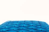 一张以中性背景为背景的蓝色纹理织物枕头的极简主义特写照片