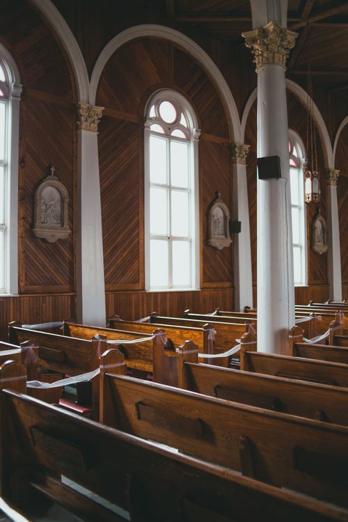 Free Peaceful church interior showcasing elegant wooden pews and tall arched windows. Stock Photo