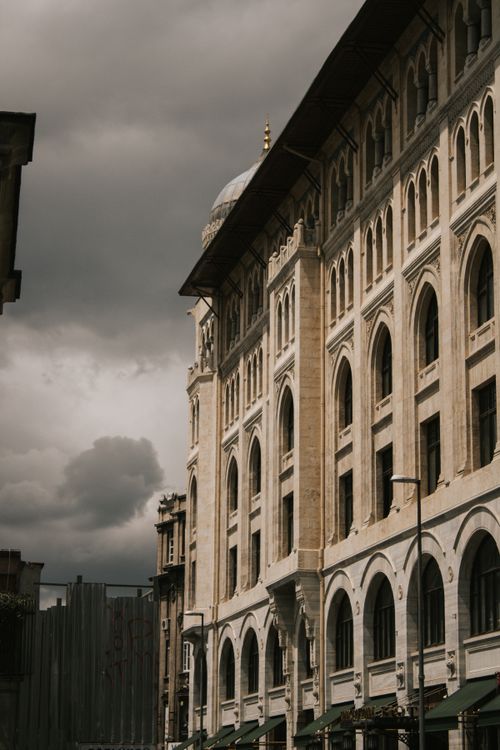 Free A grand historic building with arched windows beneath dark storm clouds, evoking drama and history. Stock Photo