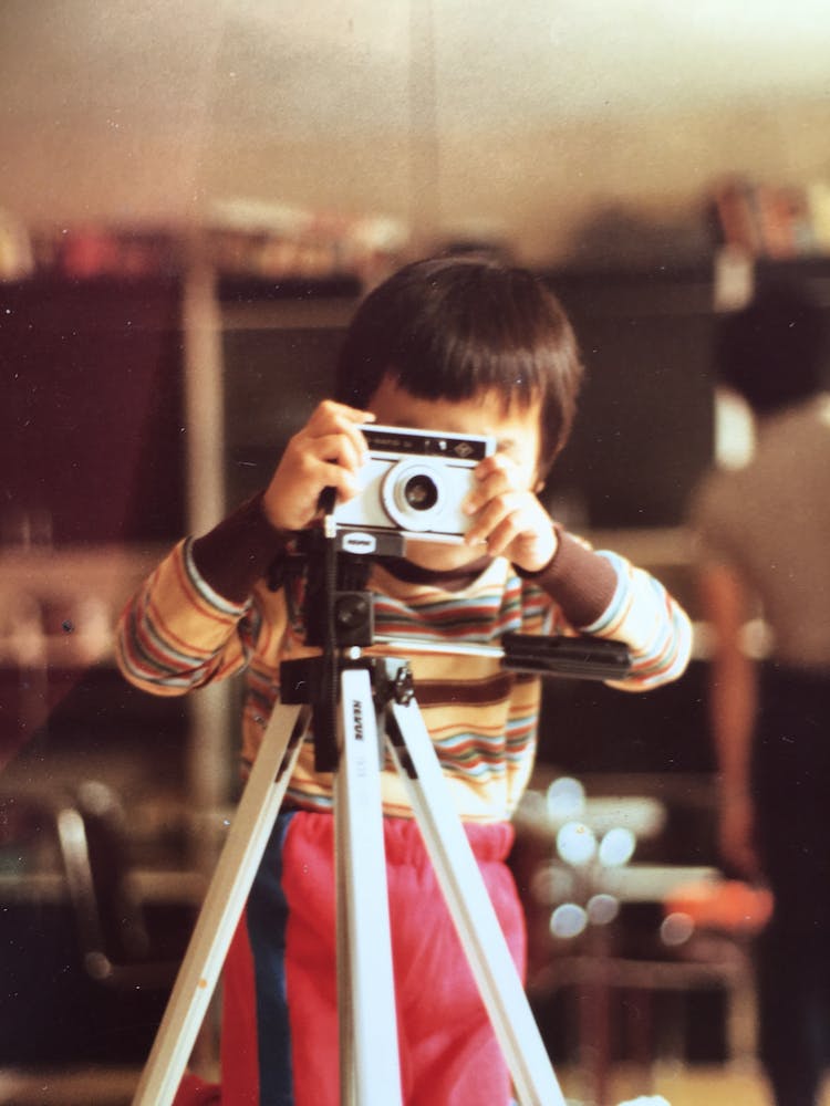 Child Taking Photo With Camera On Tripod