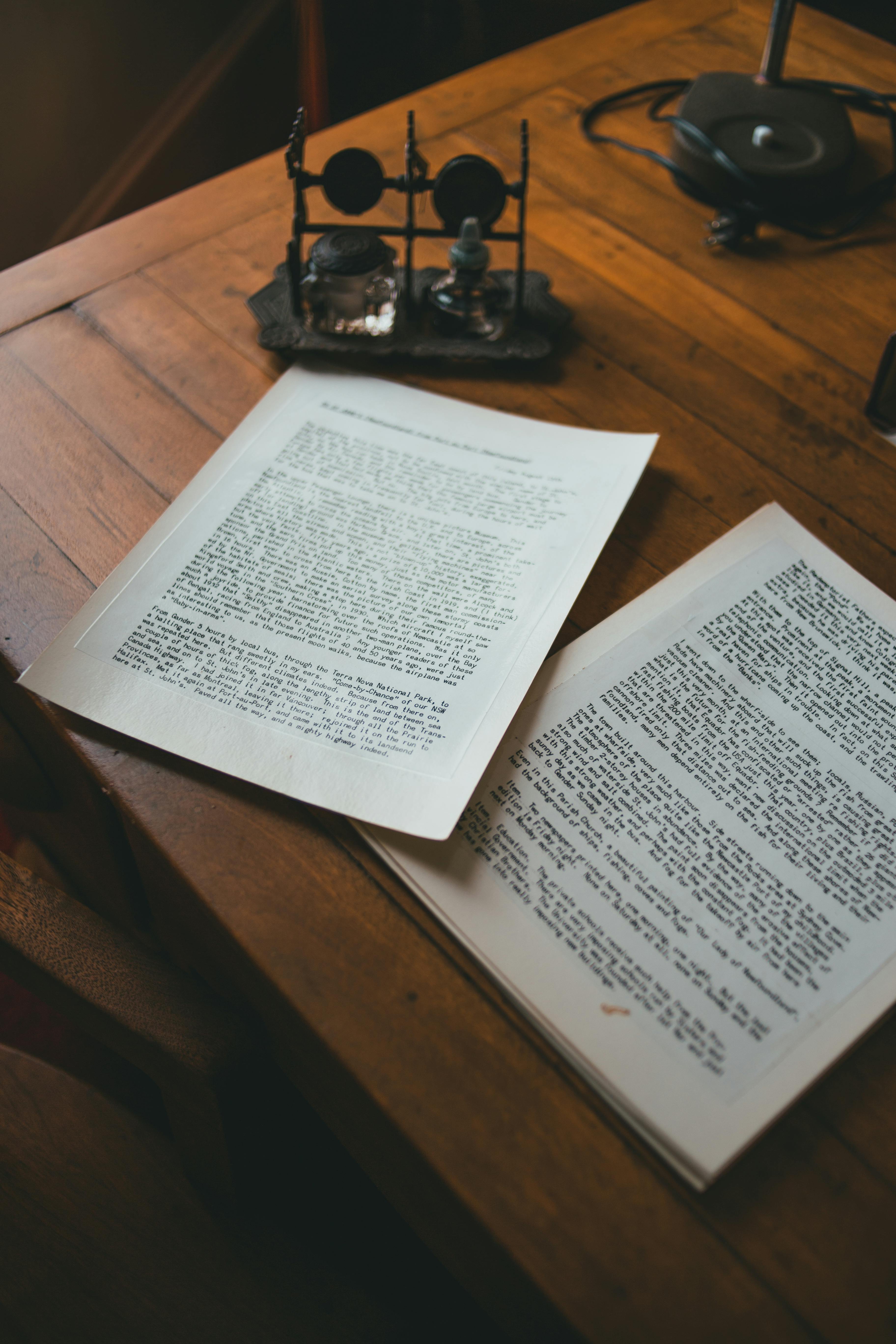 Close-up of open book pages on a wooden table with an inkwell, creating a vintage feel.