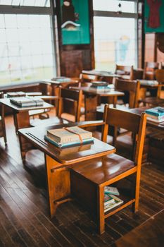 A nostalgic view of an empty vintage classroom with wooden desks and natural lighting.