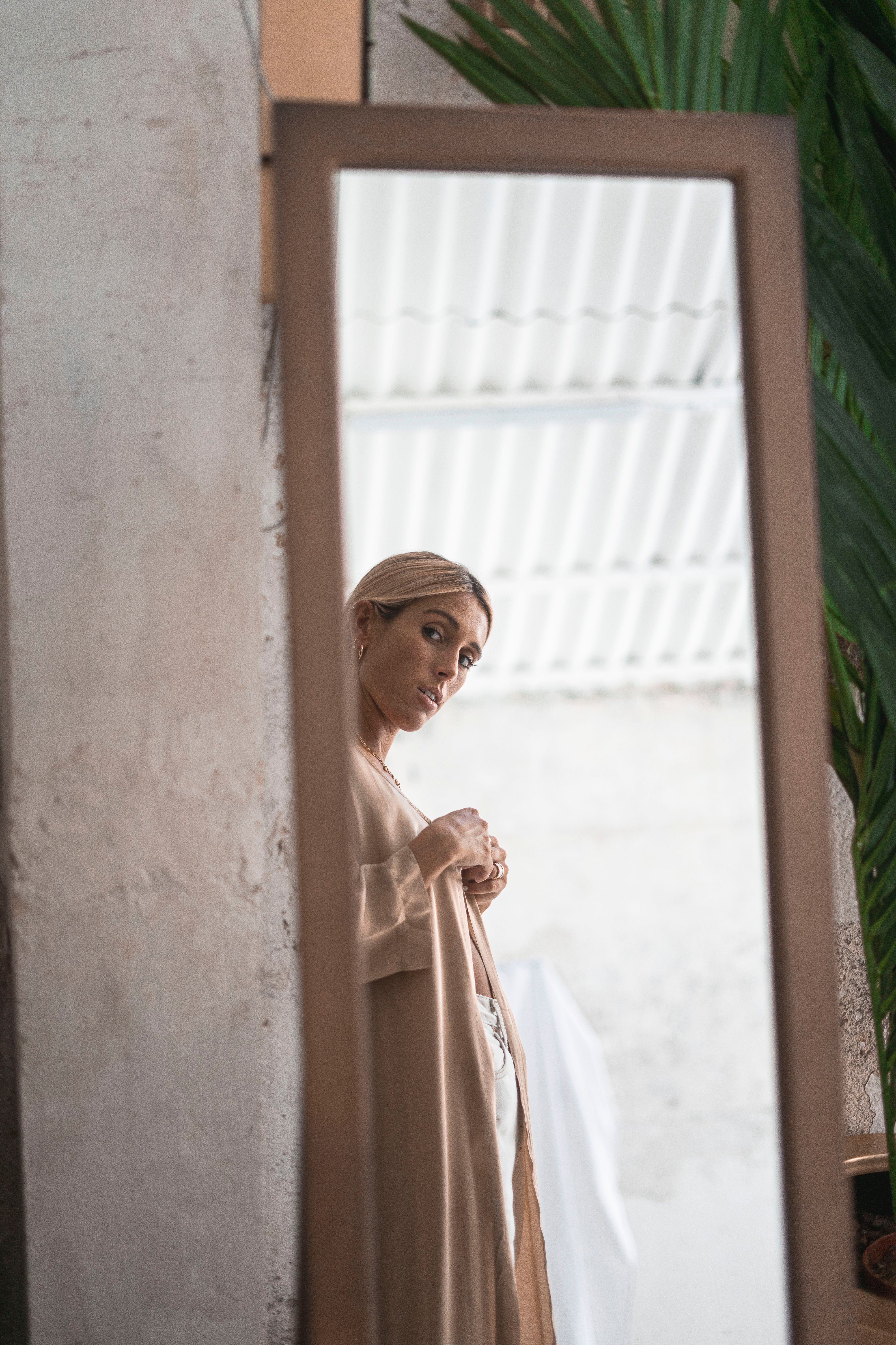 Woman gazes into a mirror in an artistic indoor setting, highlighting introspection.