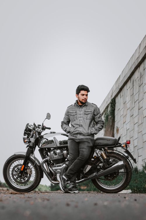 Free Young man in a jacket stands by his motorcycle, creating a cool urban vibe. Stock Photo