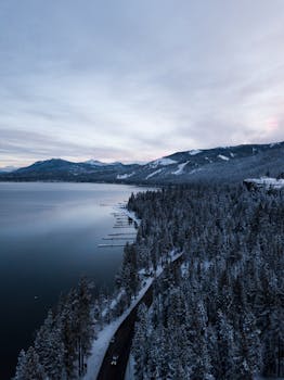 多云的天空下，俯瞰白雪皑皑的迷人森林、群山环绕的宁静湖泊