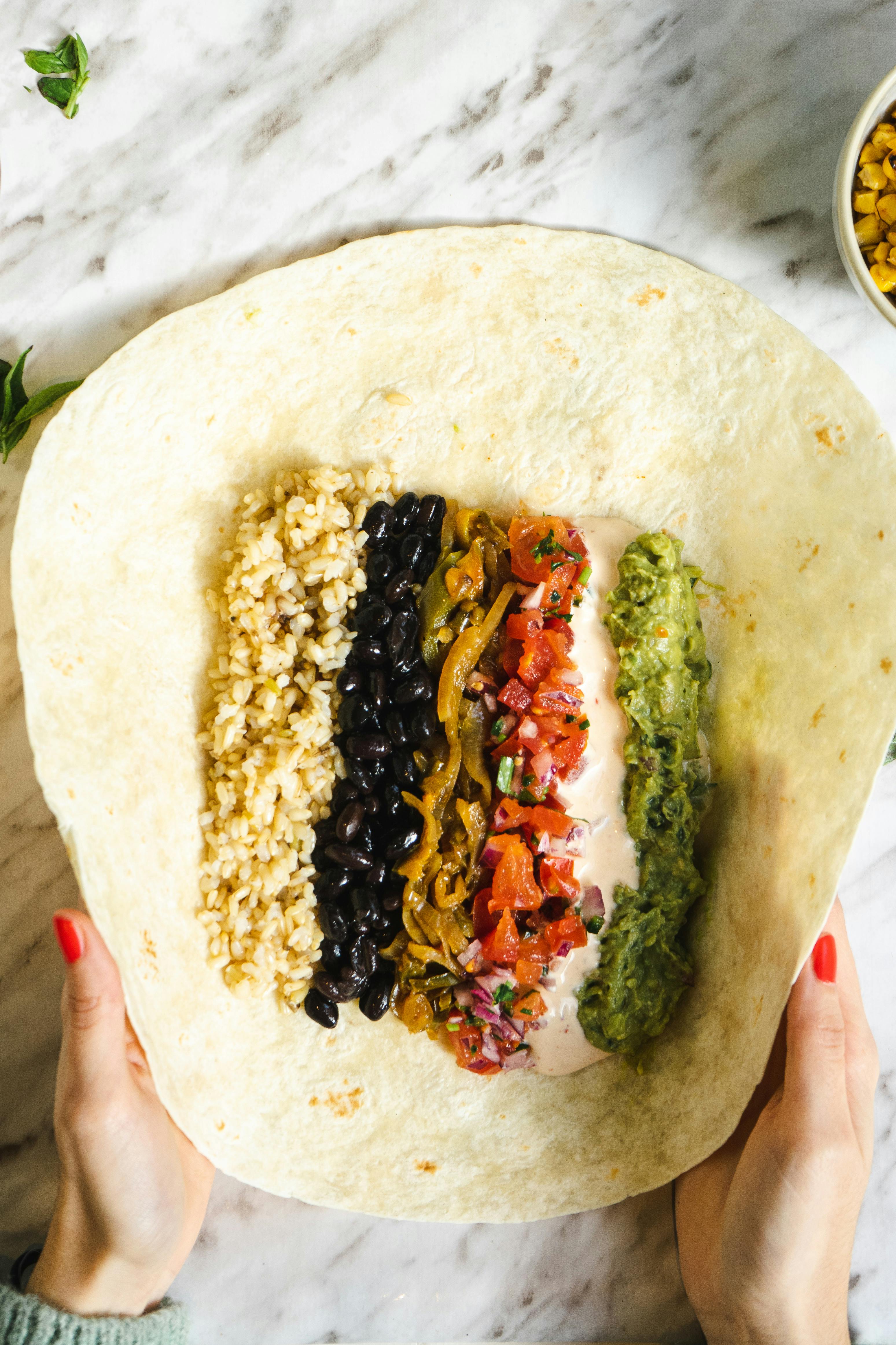 Top view of a delicious Mexican burrito with beans, rice, veggies, and guacamole.