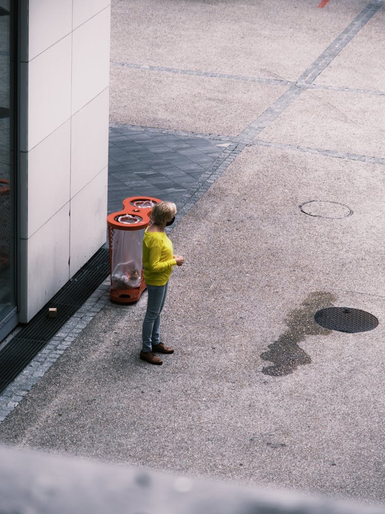 Woman Standing By Garbage Bins