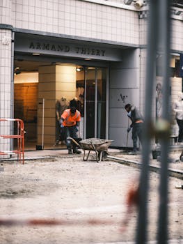 Men working on an urban construction site outside a clothing store in daylight.