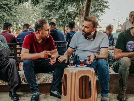 Men enjoying a conversation and tea outdoors in an urban setting. Casual atmosphere.