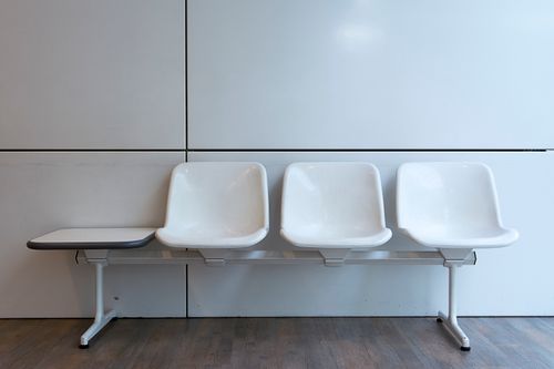 Free A minimalist setup of white plastic waiting room chairs in a modern interior. Stock Photo