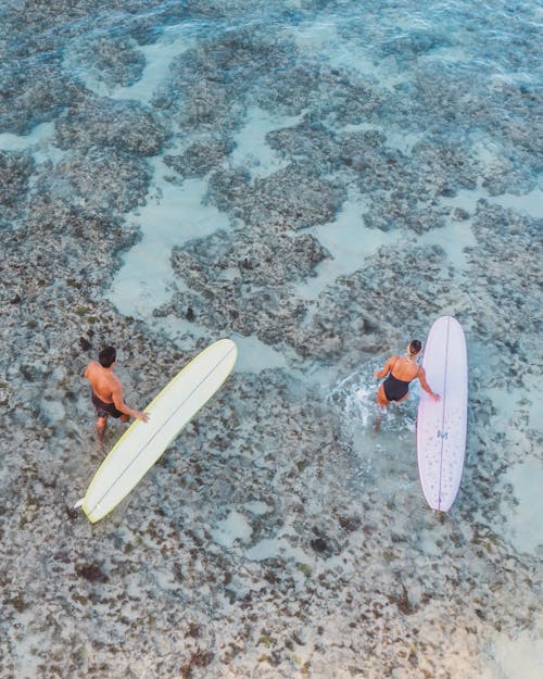 Two People Holding Surfboards
