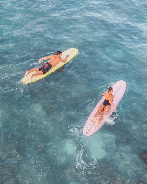 Aerial View of Man and Woman Lying on Their Surfboards 