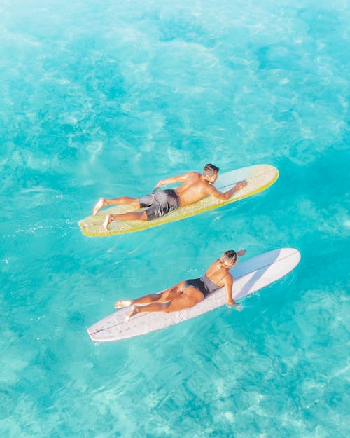 Man and Woman Paddling on Surfboards