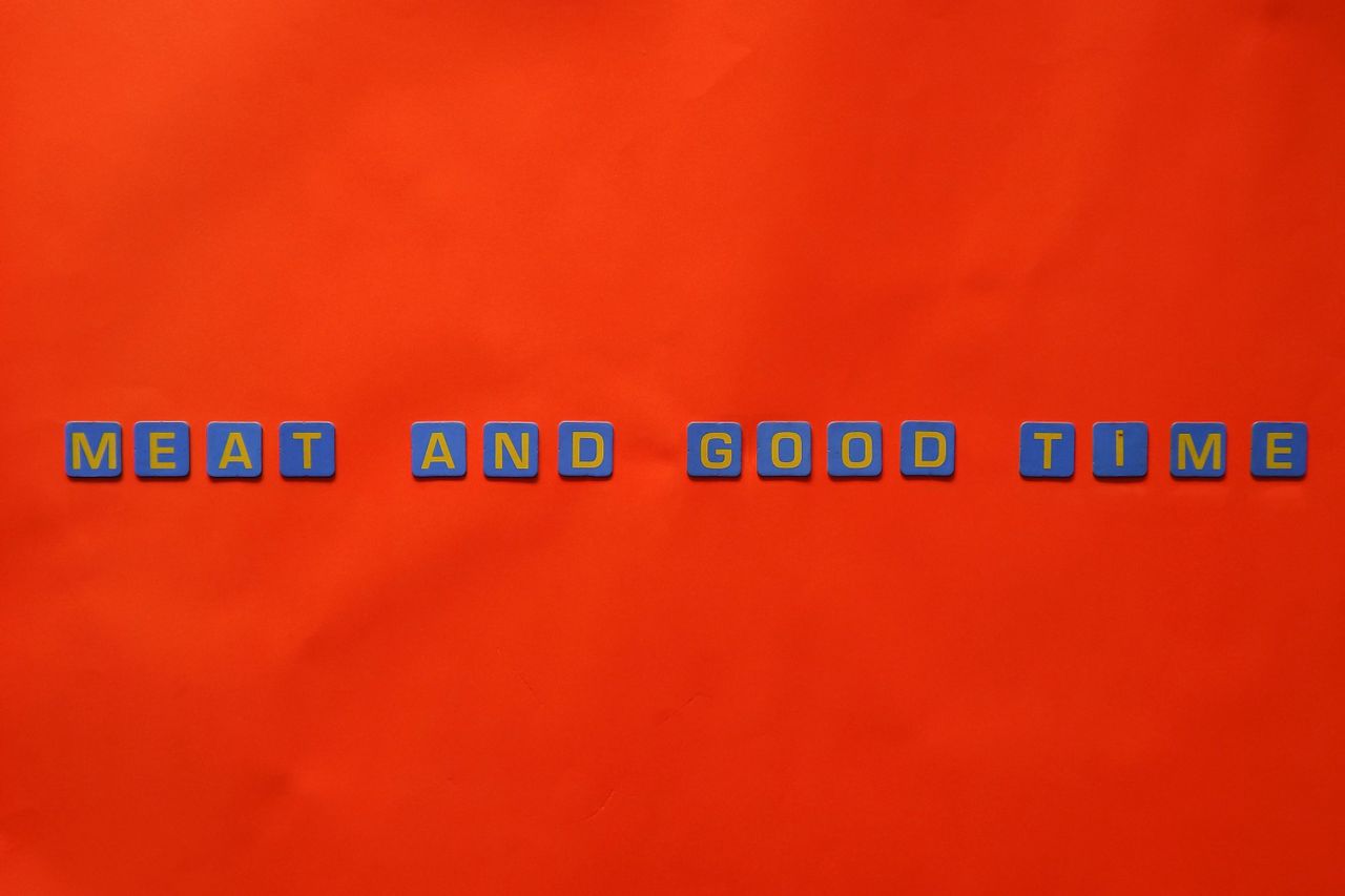 blue and yellow letter blocks spelling meat and good time on a red bac