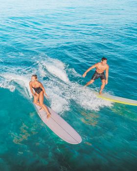Two surfers enjoy a sunny day, capturing the thrill of riding the ocean waves from above.