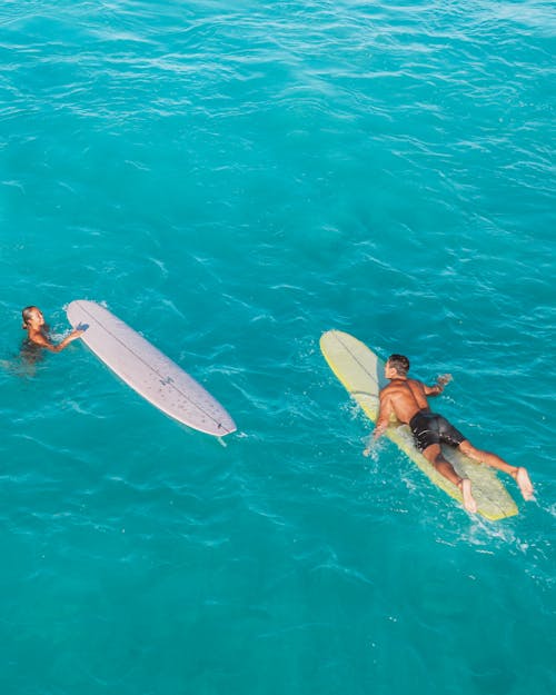 Two Surfboards and a Man in Turquoise Water