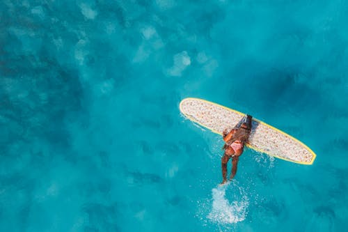 Woman Holding on a White Surfboard on Water 