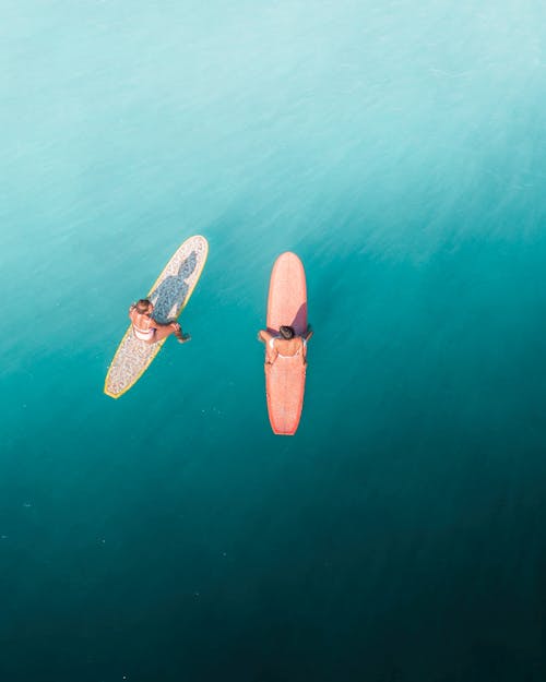 Two People Sitting on Surfboards on Water