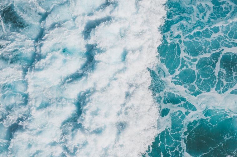 Aerial view of turquoise ocean waves and white sea foam — photo by Jess Loiterton on Pexels