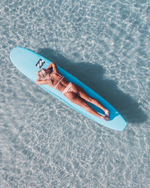 Woman Sunbathing on a Surfboard in the Sea