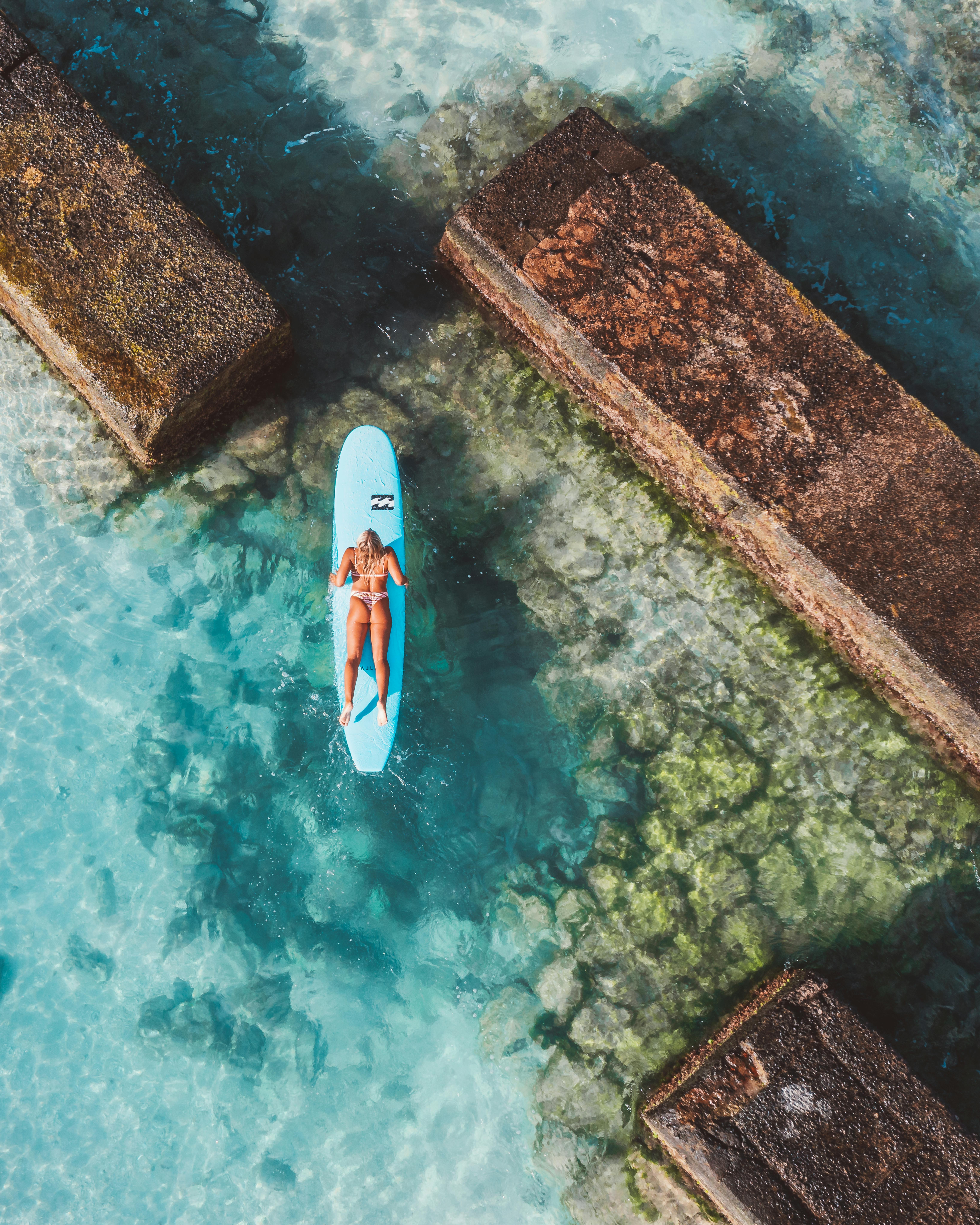 冲浪板上的一名妇女在被海堤包围的清澈蓝色的海水中航行