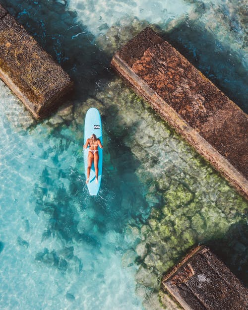 A Woman in Bikini Lying Prone Position on a Surfboard