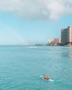 Woman in White Bikini Lying on Blue Surfboard on Sea