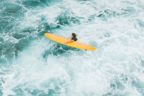 Man with a Yellow Surfboard in Rough Turquoise Water