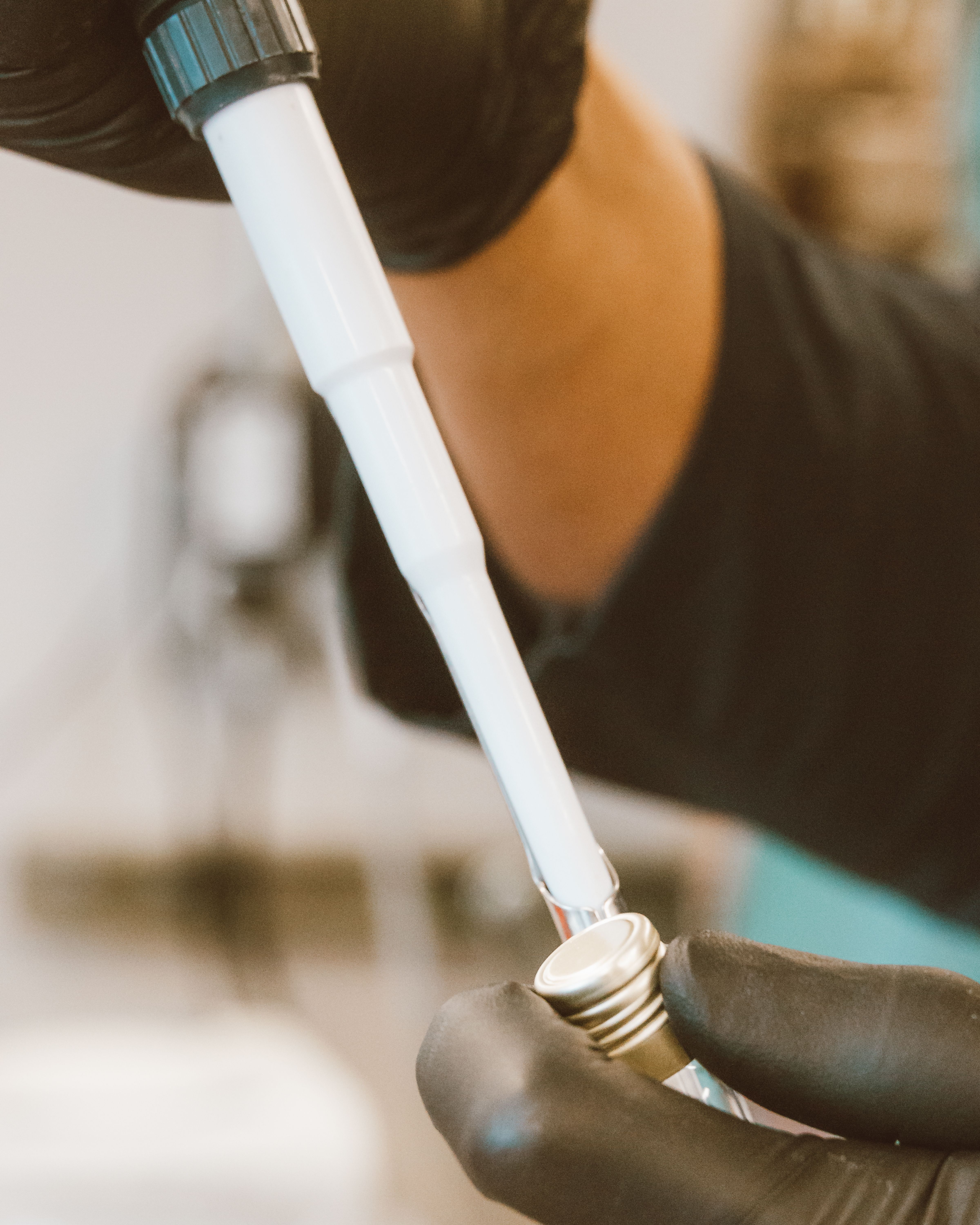 A close-up of gloved hands holding a laboratory test tube in a scientific setting.