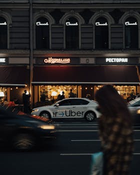 City evening scene with cars passing by a restaurant, showcasing urban nightlife.