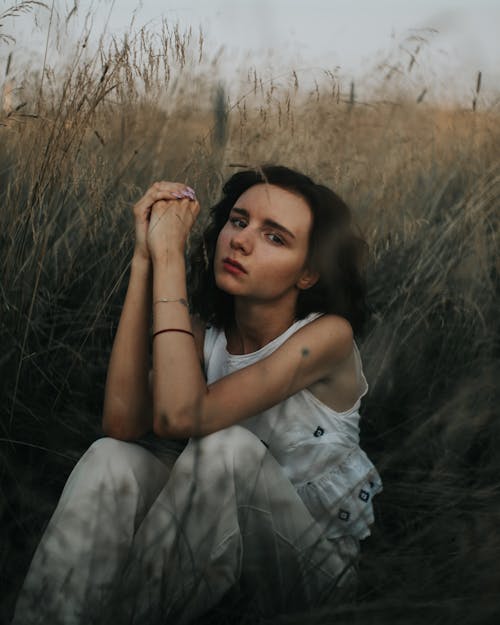 Woman Sitting among Grasses