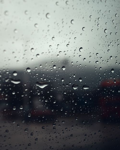 Free Close-up of raindrops on a glass window, capturing a moody rainy day atmosphere. Stock Photo