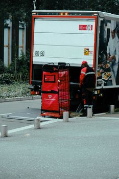 A delivery worker unloads a truck on a street, showcasing efficient logistics.