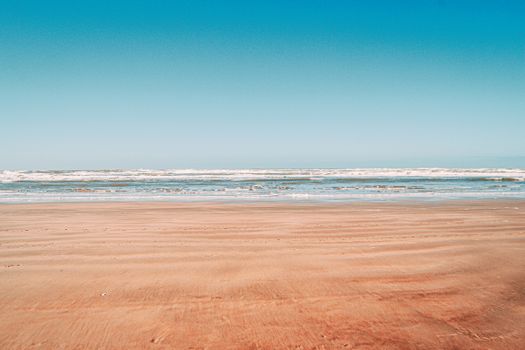 A tranquil beach scene featuring gentle waves and a clear blue sky, ideal for relaxation themes.