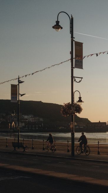 Cyclists enjoy a peaceful ride along a waterfront promenade at sunset, capturing a serene evening scene.