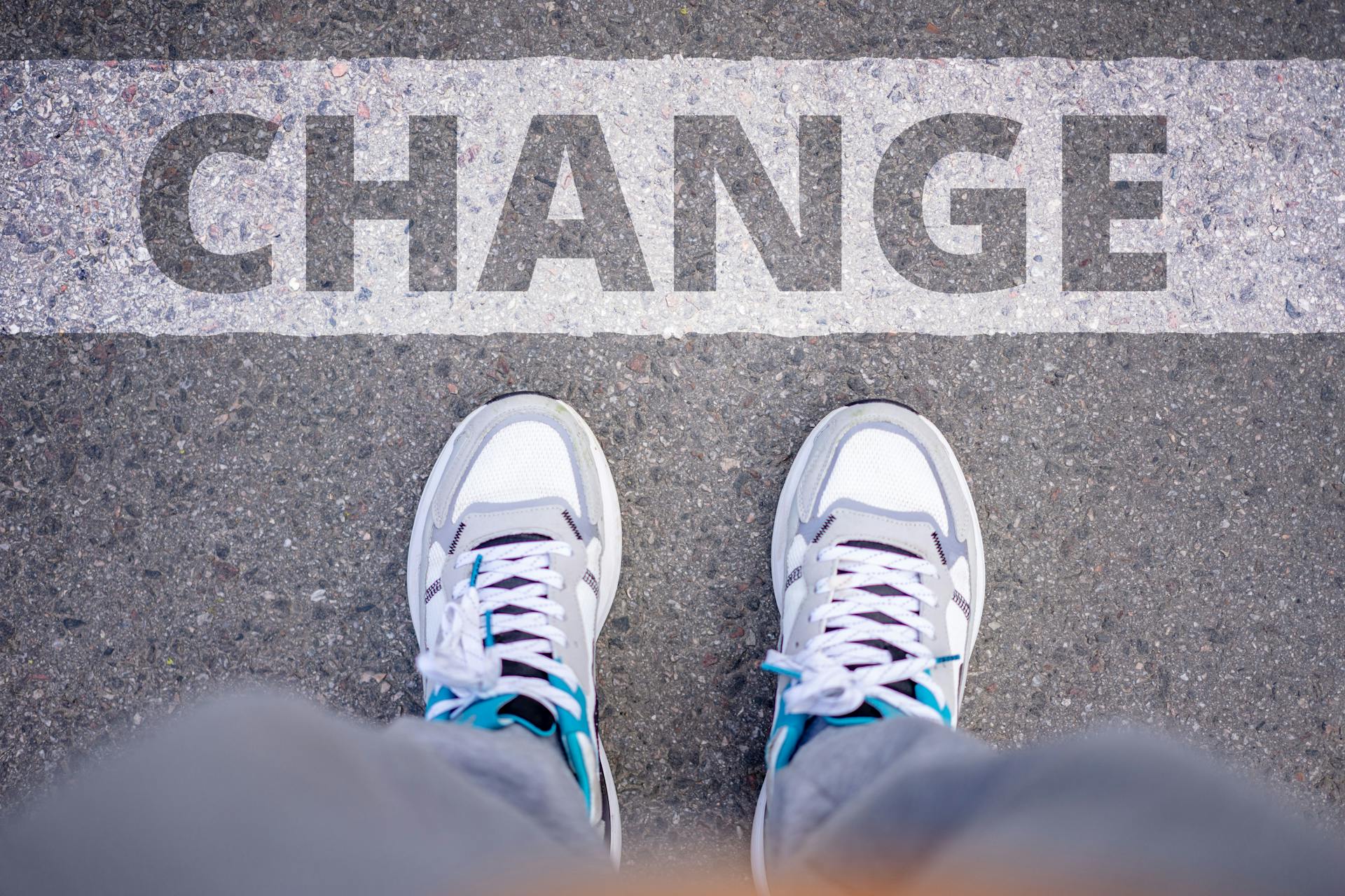 Close-up of sneakers on street with 'Change' text, symbolizing transformation.