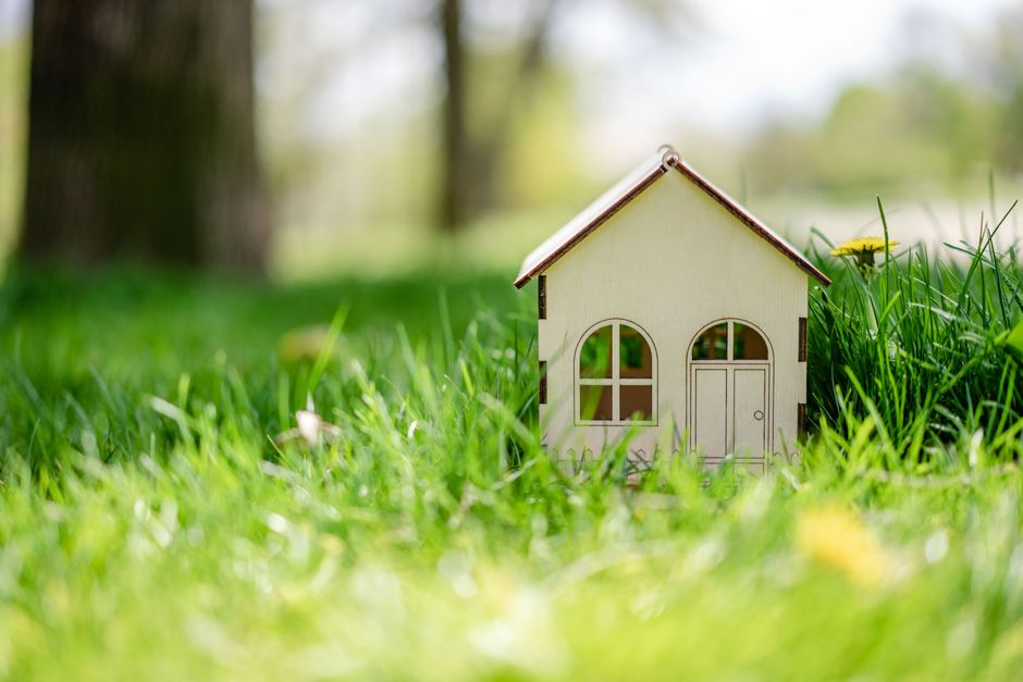 Close-up of a small toy house nestled in vibrant green grass, depicting a playful outdoor scene.