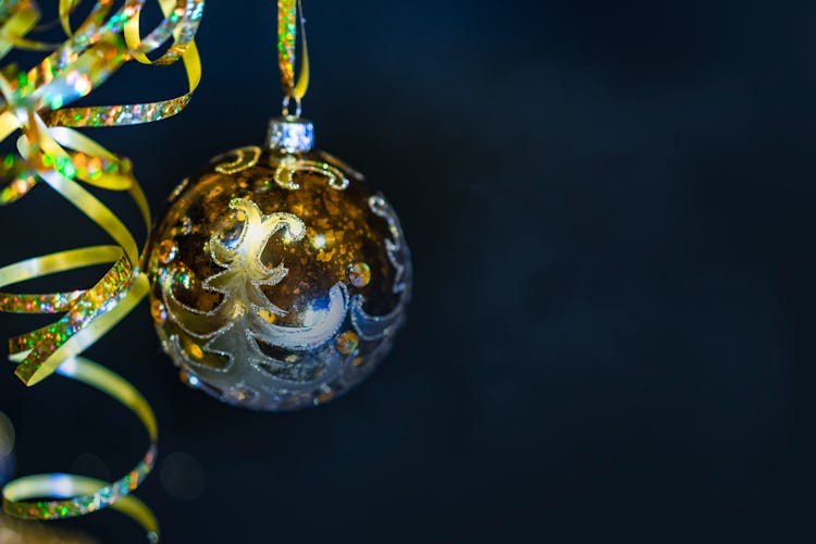 Yellow Bauble Hanging On A Ribbon Against Black Background