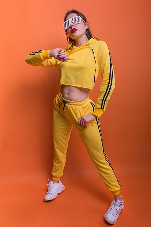 Woman Wearing Yellow Sports Overall Posing against Orange Background