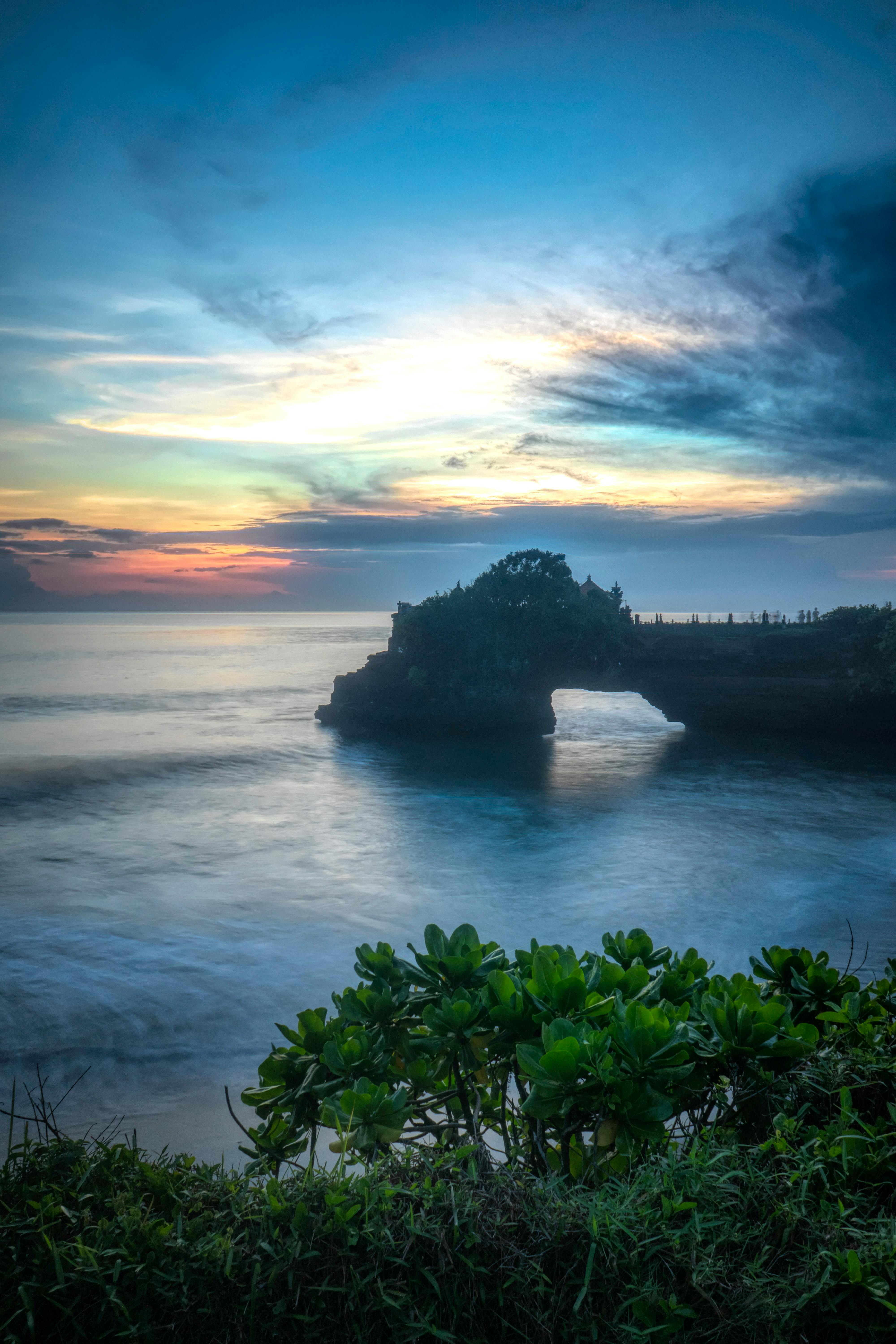 Tanah Lot sea temple Bali silhouetted against a dramatic sunset sky over the ocean