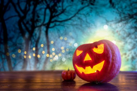 A carved pumpkin jack-o'-lantern glowing on a wooden surface during Halloween night.