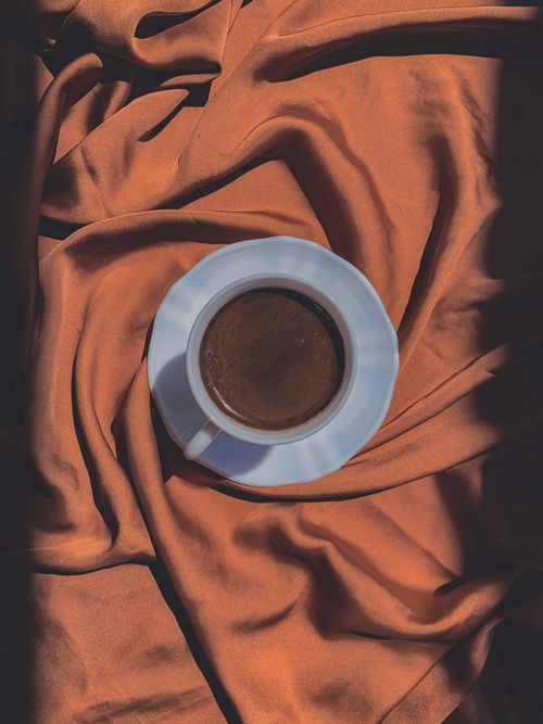 Free Top-down view of a coffee cup on orange fabric, capturing a warm and cozy atmosphere. Stock Photo