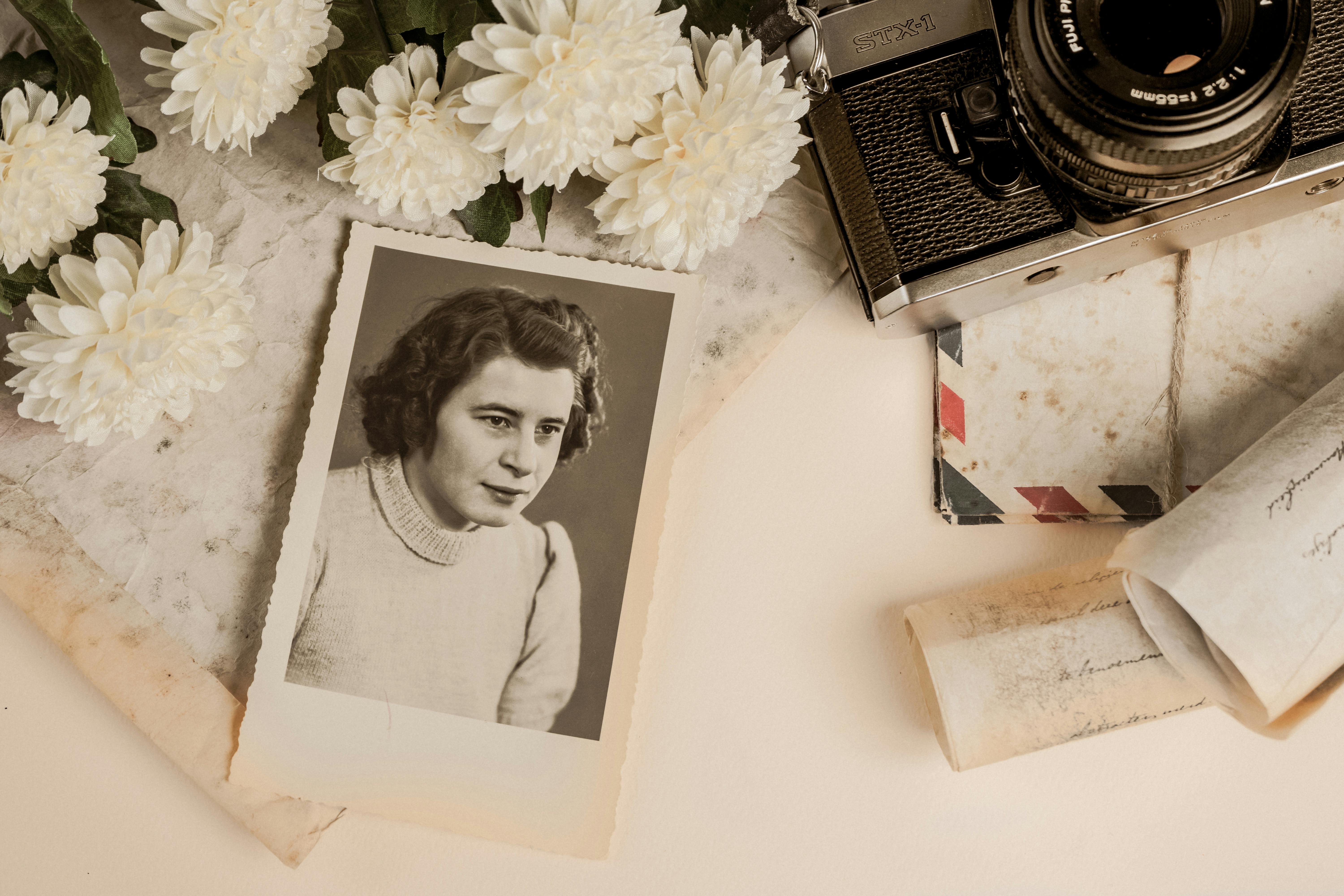 A nostalgic composition featuring a vintage photograph, old camera, and white flowers.