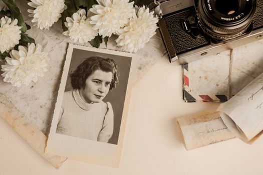 A nostalgic composition featuring a vintage photograph, old camera, and white flowers.