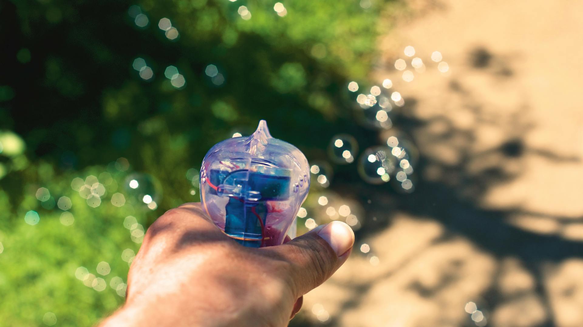 Person Holding White and Blue Plastic Bubble Dispensing Gun