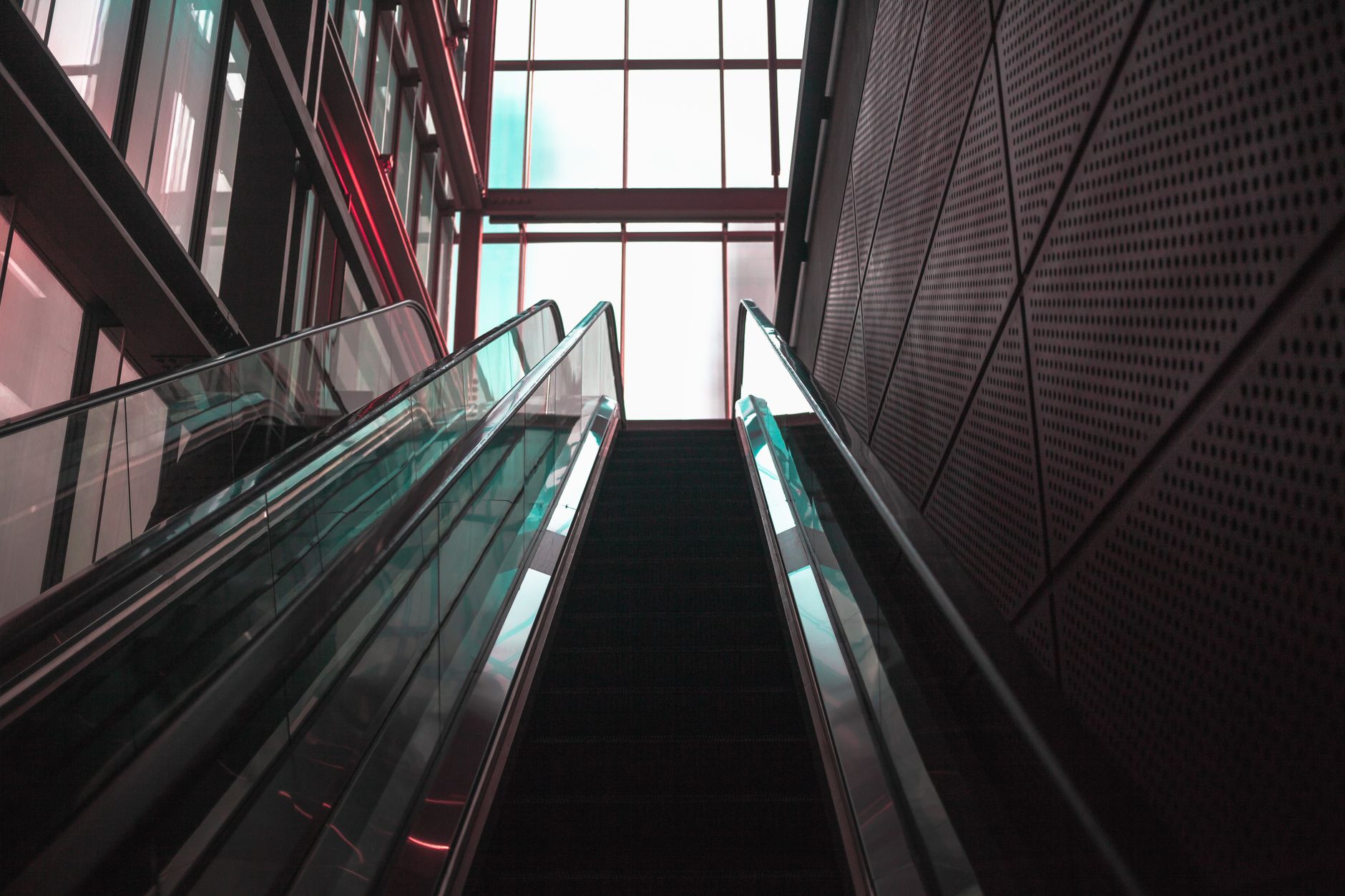 Upward view of a modern escalator with sleek architecture, emphasizing perspective and symmetry.