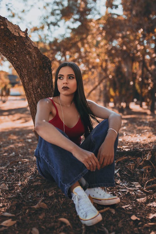 A Woman in Blue Denim Jeans Sitting on the Ground