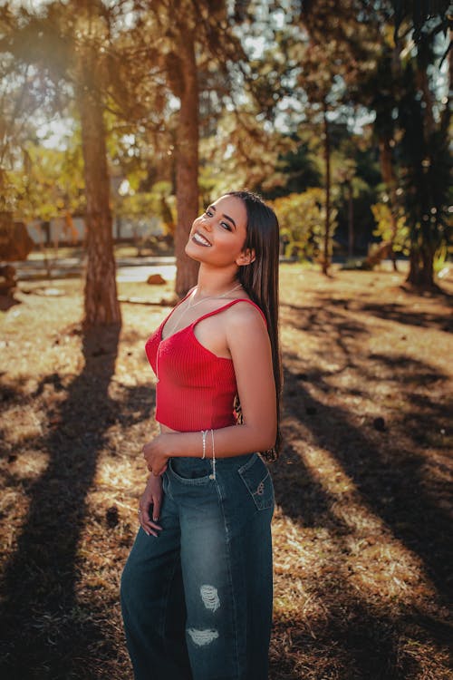 Woman in Red Tank Top and Blue Denim Jeans Smiling
