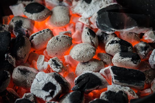 Close-up of glowing charcoal briquettes ready for outdoor barbecue grilling.