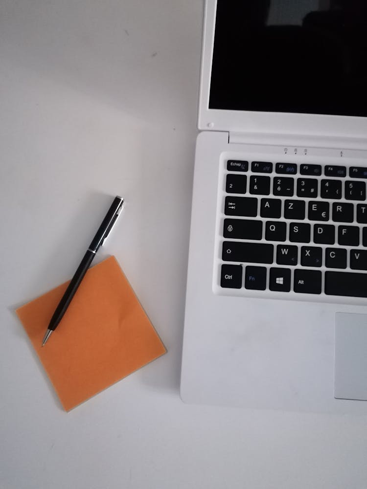 Black Pen And Memo Pad Beside The Laptop